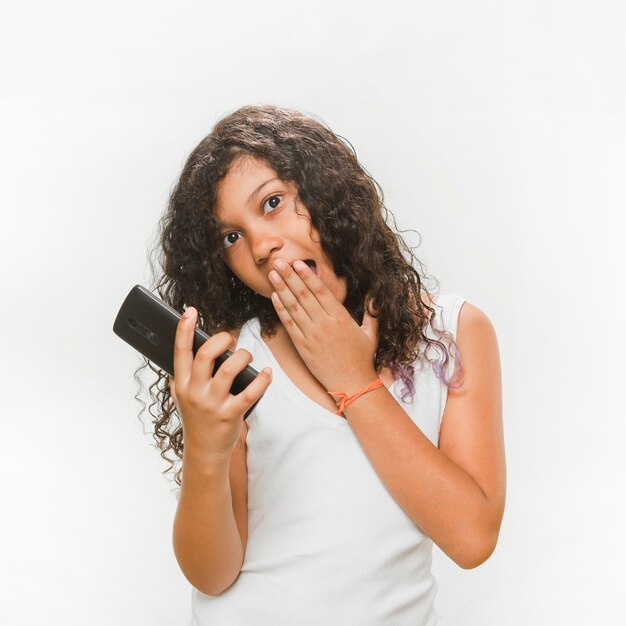 Chica sorprendida sosteniendo teléfono móvil