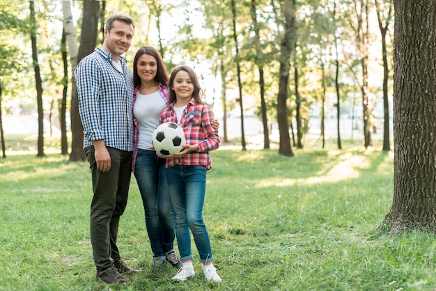 Chica sosteniendo el balón de fútbol de pie con su padre en el parque