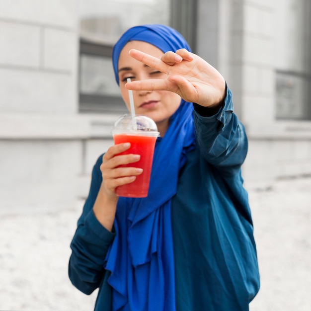 Chica sosteniendo un batido mientras hace el signo de la paz