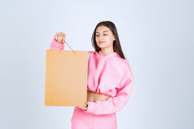 Foto gratuita chica sosteniendo una bolsa de cartón y mirándola.