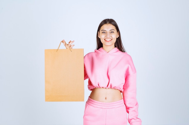 Chica sosteniendo una bolsa de cartón y sintiéndose emocionada.