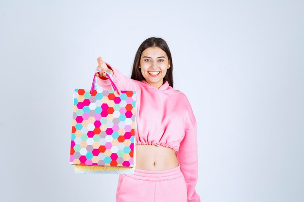 Chica sosteniendo bolsas de colores y parece emocionada.