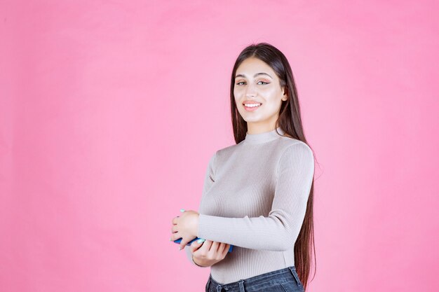 Chica sosteniendo una caja de regalo azul y sonriendo