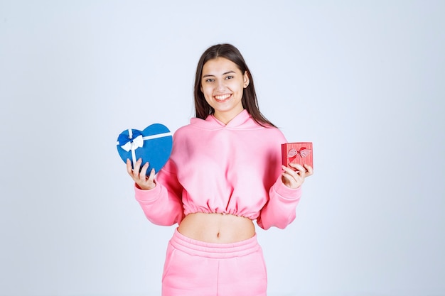 Chica sosteniendo cajas de regalo azules y rojas en ambas manos.