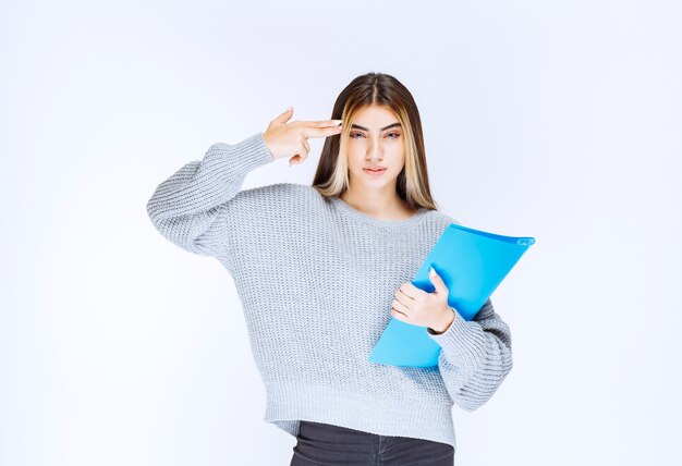 Chica sosteniendo una carpeta de informe azul y pensando.