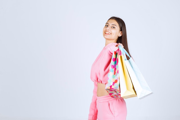 Chica sosteniendo coloridos bolsos de compras en su hombro.