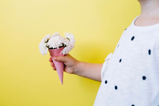 Chica sosteniendo cono con flores elegantes