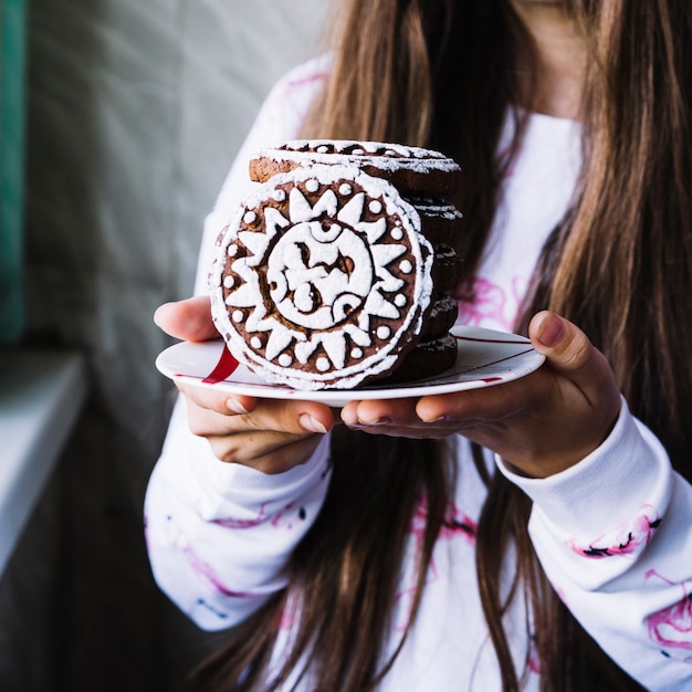 Foto gratuita chica sosteniendo cookies de glaseado en placa