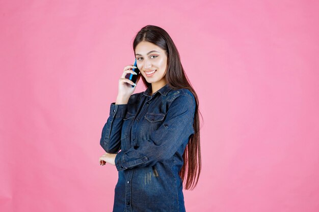 Chica sosteniendo hablando con su teléfono inteligente azul