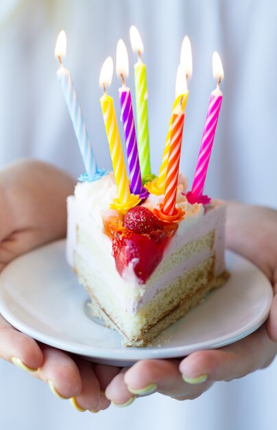 Chica sosteniendo hermosos apetitosos pastel de cumpleaños con muchas velas. De cerca.