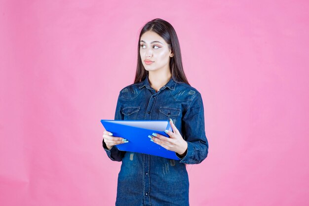 Chica sosteniendo un informe comercial y pensando