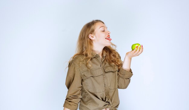 Chica sosteniendo una manzana verde en la palma.