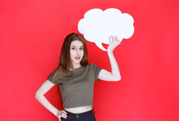 Chica sosteniendo y presentando un tablero de información de forma de nube.