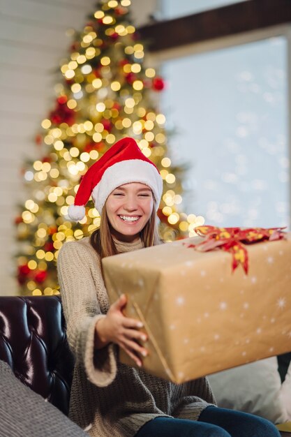 Chica sosteniendo un regalo de Navidad en Nochevieja. Niña, mirar la cámara