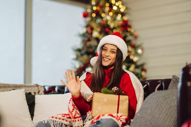 Chica sosteniendo un regalo de Navidad en Nochevieja. Niña, mirar la cámara