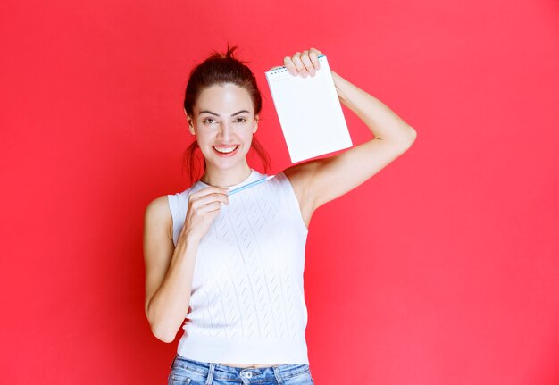 Chica sosteniendo su hoja de examen y apuntando a ella.