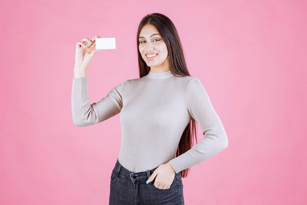 Chica sosteniendo su nueva tarjeta de visita y sintiéndose positiva