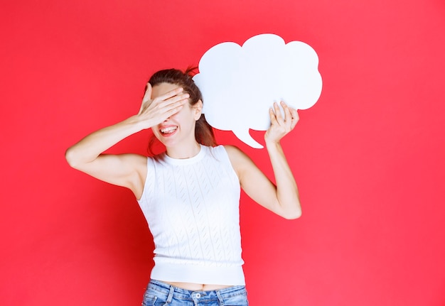 Chica sosteniendo un tablero de ideas en forma de nube en blanco y parece agotado.