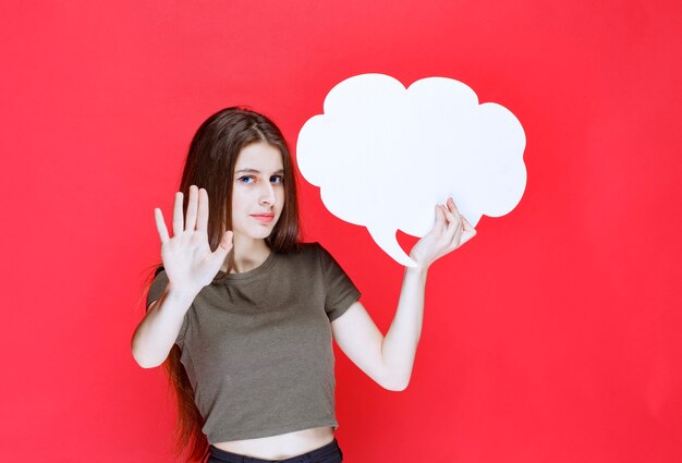 Chica sosteniendo un tablero de información de forma de nube y negándose a usarlo.