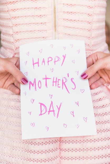 Foto gratuita chica sosteniendo la tarjeta de felicitación con la inscripción del día de las madres felices