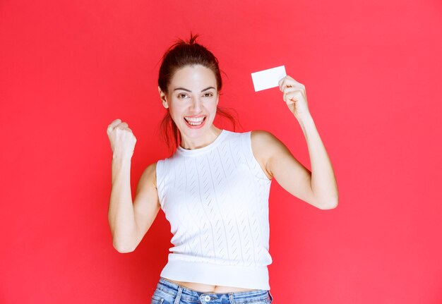 Chica sosteniendo una tarjeta de visita y disfrutando de su nueva posición.