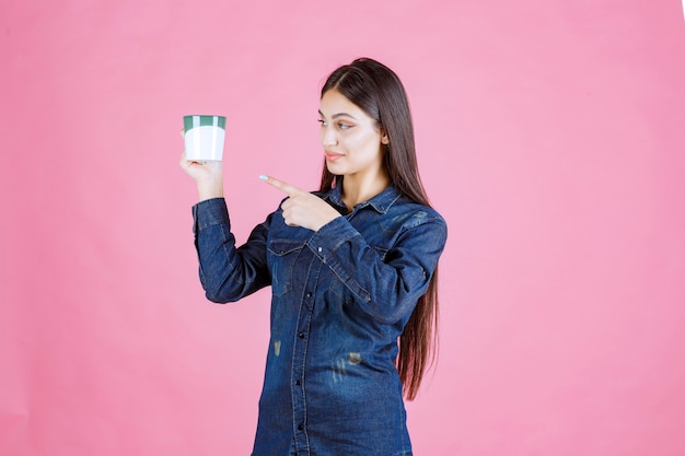 Chica sosteniendo una taza de café y apuntando a ella