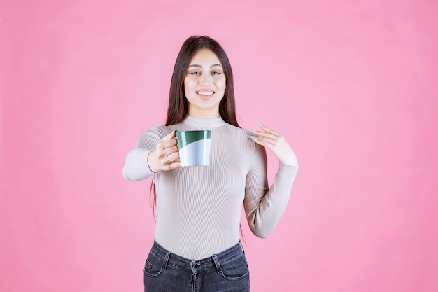 Chica sosteniendo una taza de café de color verde blanco y sintiéndose positivo