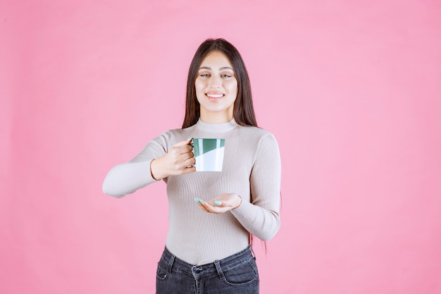 Chica sosteniendo una taza de café de color verde blanco y sintiéndose positivo