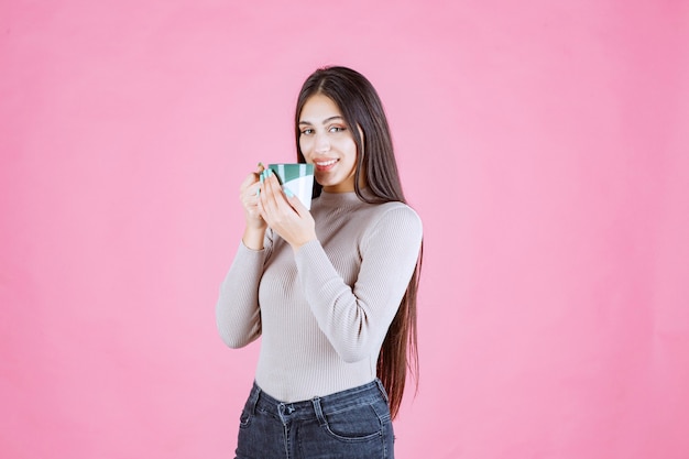 Chica sosteniendo una taza de café de color verde blanco y sintiéndose positivo