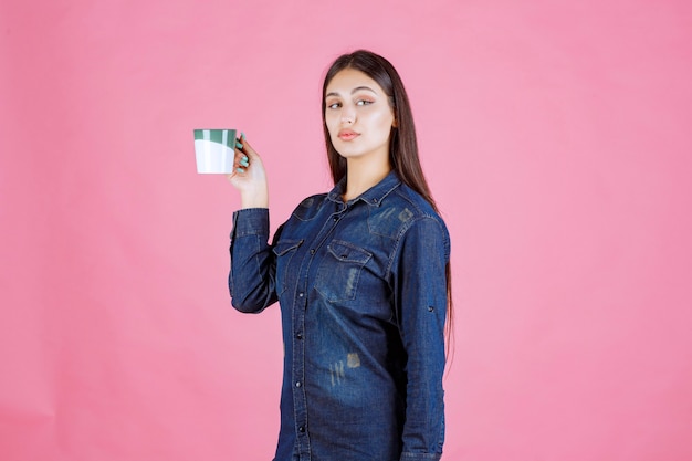 Chica sosteniendo una taza de café verde blanco y oliendo