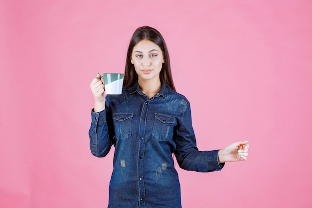 Chica sosteniendo una taza de café verde blanco y oliendo