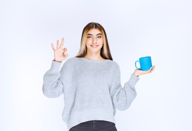 Chica sosteniendo una taza de té azul y disfrutando del sabor.