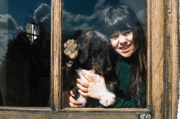 Chica con su perro mirando a través de la puerta de cristal