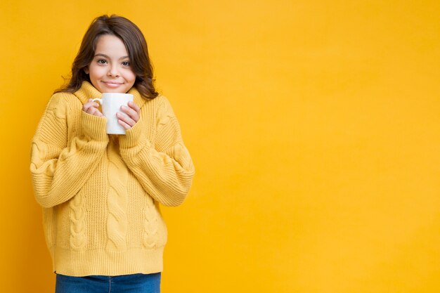 Chica de suéter amarillo con copa en las manos