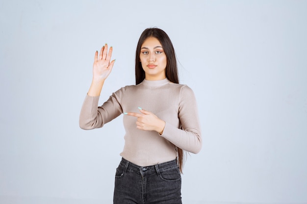 Foto gratuita chica de suéter gris levantando las manos.