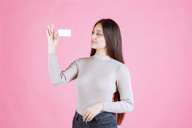 Chica en suéter gris mostrando y presentando su tarjeta de visita