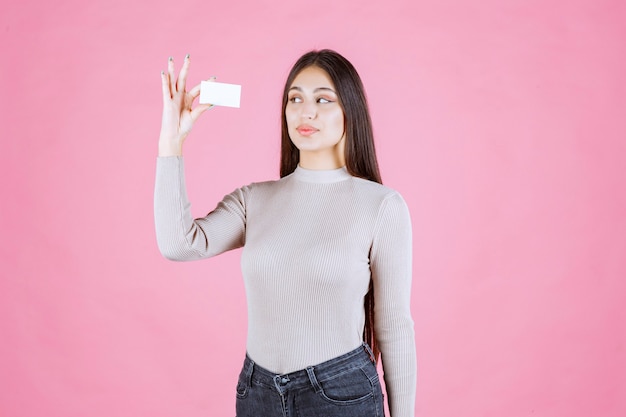 Foto gratuita chica en suéter gris mostrando y presentando su tarjeta de visita