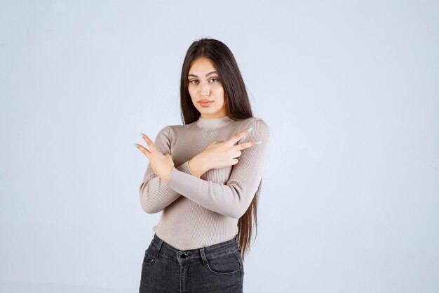 Chica en suéter gris que muestra el signo de la paz.