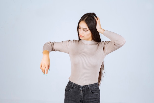 Chica en suéter gris sosteniendo su cara y cabeza.