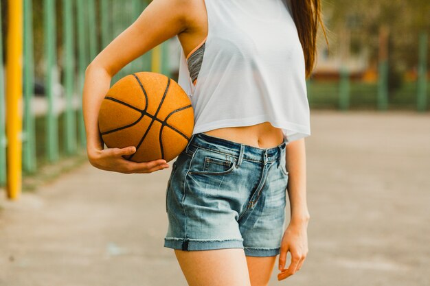 Chica sujetando baloncesto en entorno urbano