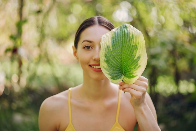 Chica sujetando una hoja verde cerca de su cara