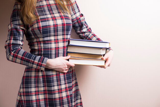 Chica sujetando libros junto a su cintura