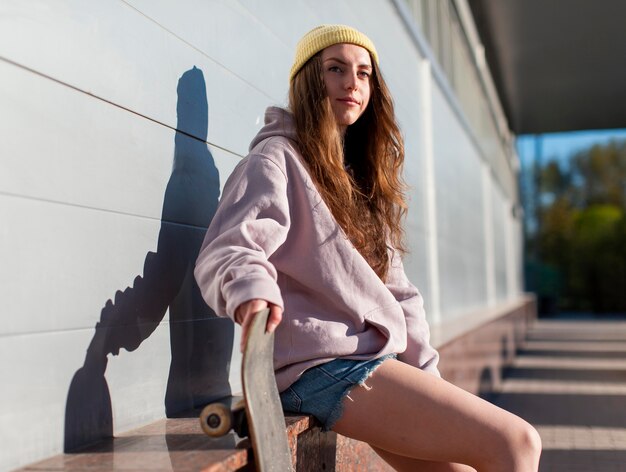 Chica sujetando patineta tiro medio