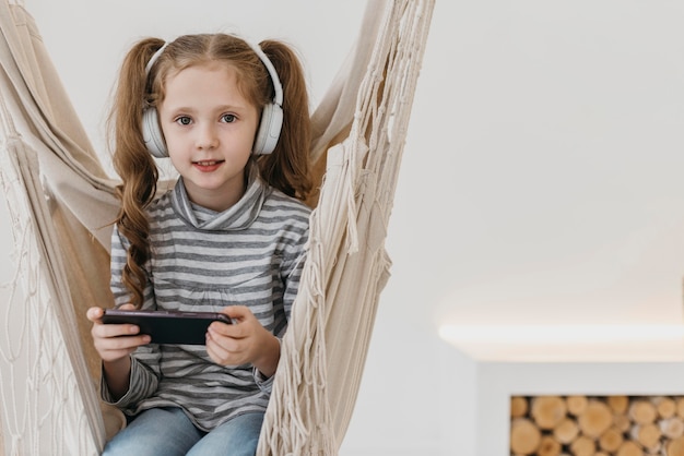 Chica sujetando el teléfono móvil y usando audífonos