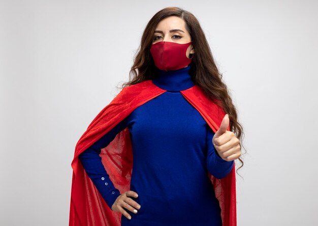 Chica de superhéroe caucásica confiada con capa roja con máscara protectora roja