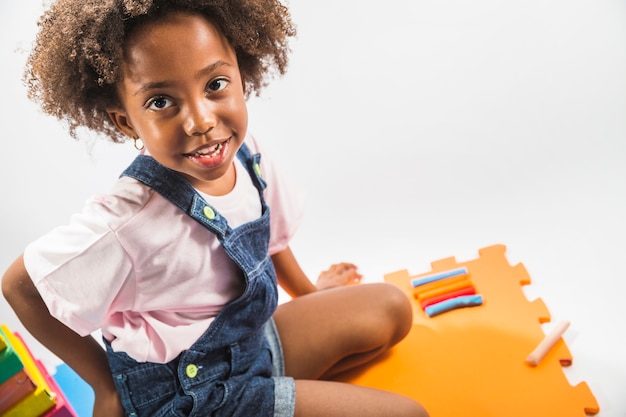 Chica en tapete de juego con plastilina en estudio