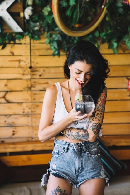 Chica con tatuaje sonriendo y bebiendo