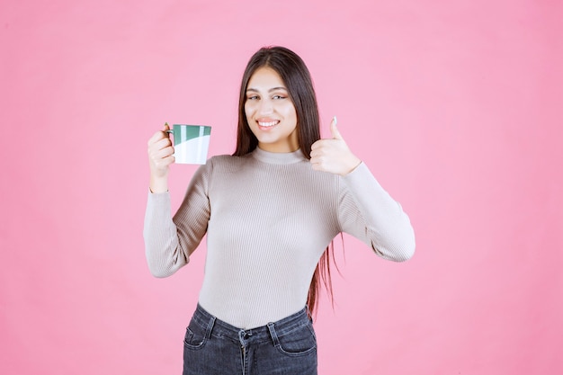 Chica con una taza de café haciendo letrero de disfrute