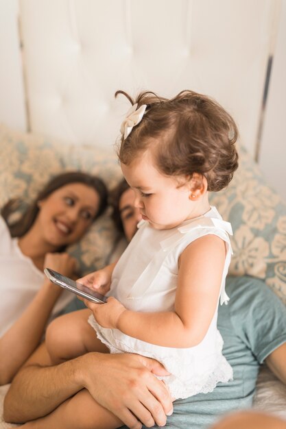 Chica con teléfono inteligente cerca de los padres