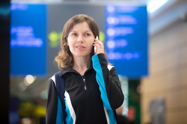 Chica en el teléfono móvil en el aeropuerto